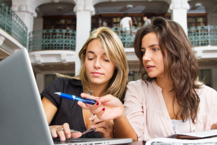 Young woman pointing with pen to laptop in library